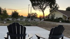 Two Adirondack chairs facing a house with a large tree in the background. - Wine Country Trail, View, Gated property, Detached Studio & Private View Patio, (Paso Robles)