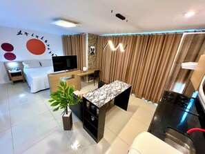 Una habitación de hotel moderna con cama, televisión, escritorio y zona de comedor.