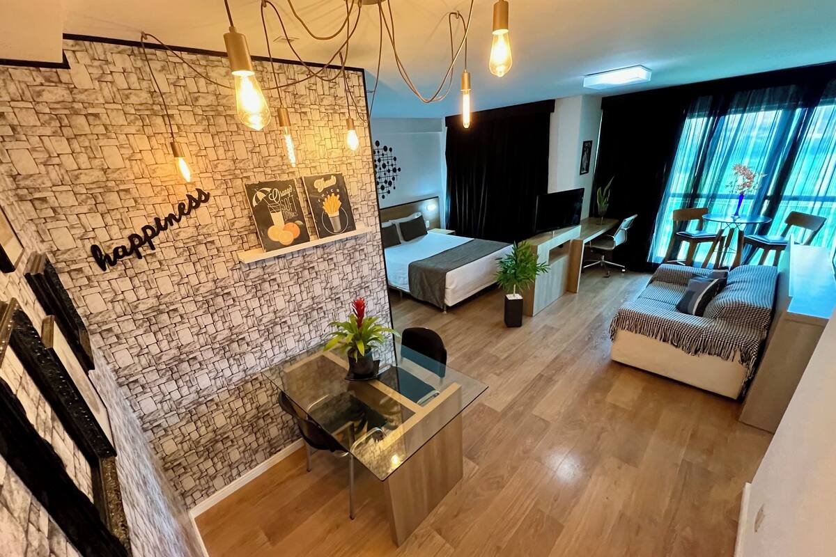 Una sala de estar moderna con una pared de piedra, una mesa de comedor de vidrio, un sofá y un televisor.