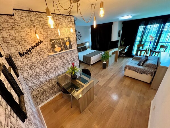 Una sala de estar moderna con una pared de piedra, una mesa de comedor de vidrio, un sofá y un televisor.