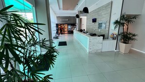 Eine geräumige Lobby mit Empfangstresen, Topfpflanzen und einem Fliesenboden.