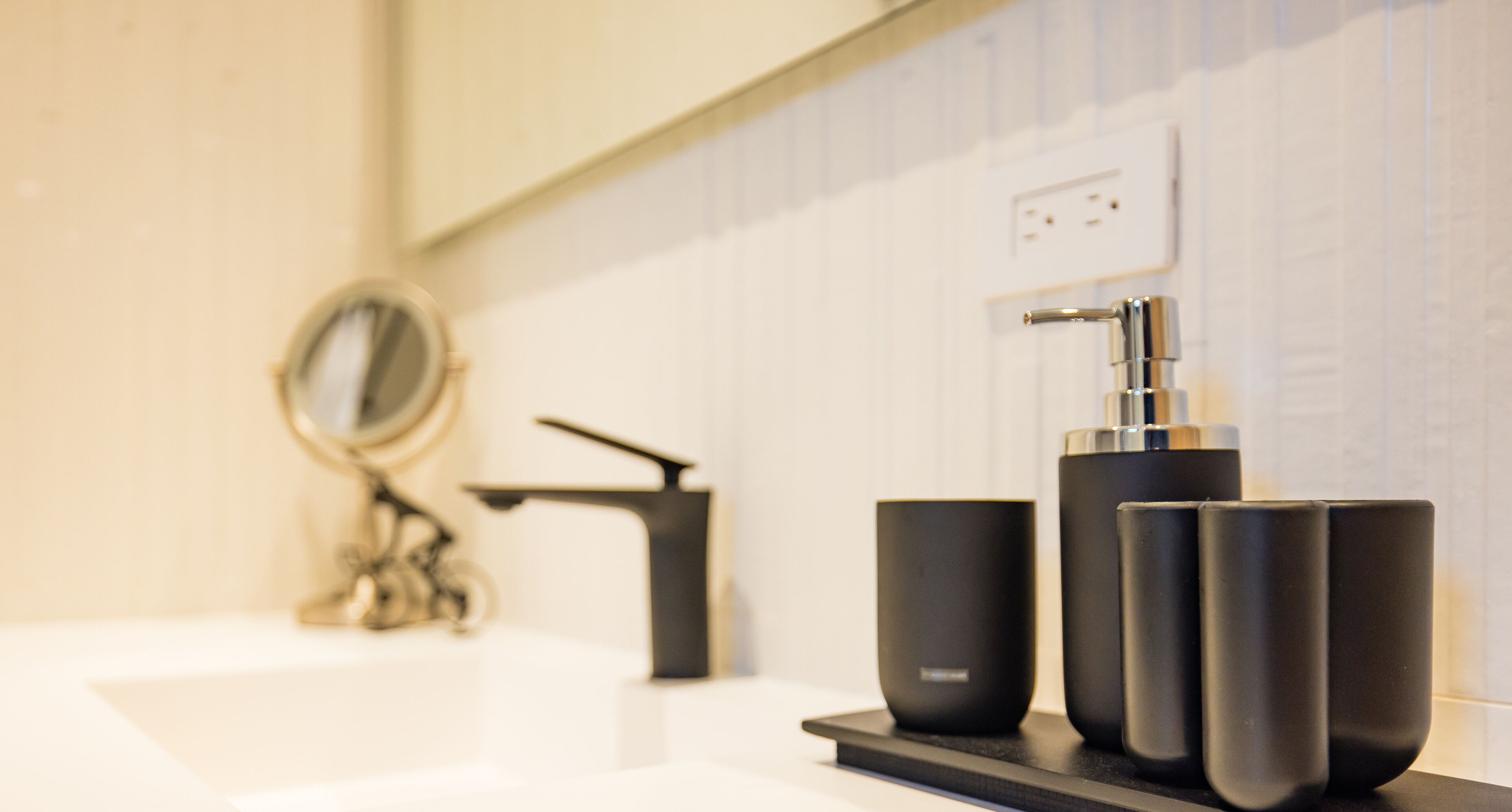 A modern bathroom with a white sink, a black faucet, and a mirror.