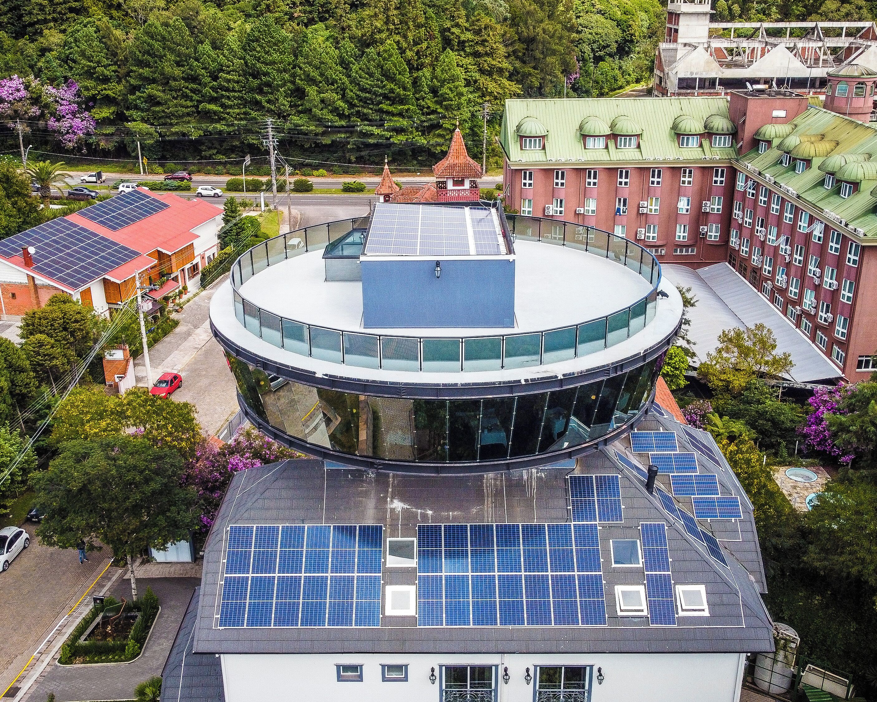 Un bâtiment circulaire à la façade en verre et doté de panneaux solaires sur le toit.
