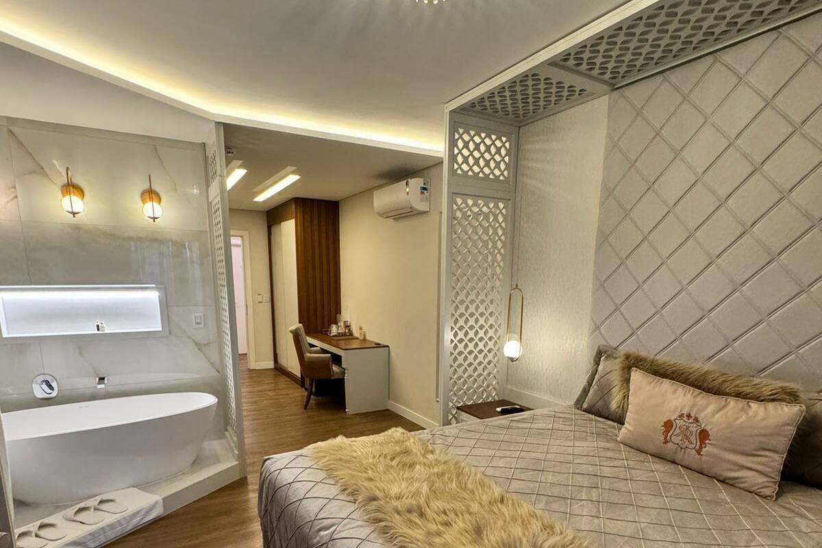 A modern bedroom with a large bed, a built-in vanity with a mirror, and a chandelier.