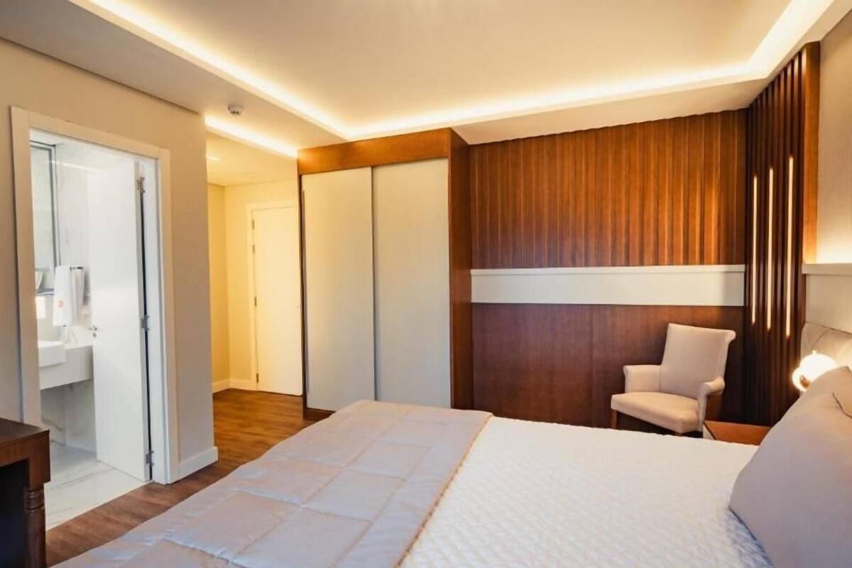 A modern bedroom with a large bed, a chair, and a wardrobe.