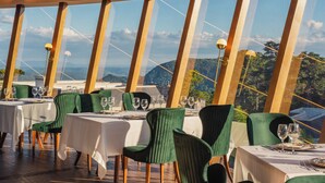 Un restaurant dont les tables sont dressées pour le service, offrant une vue sur les montagnes.