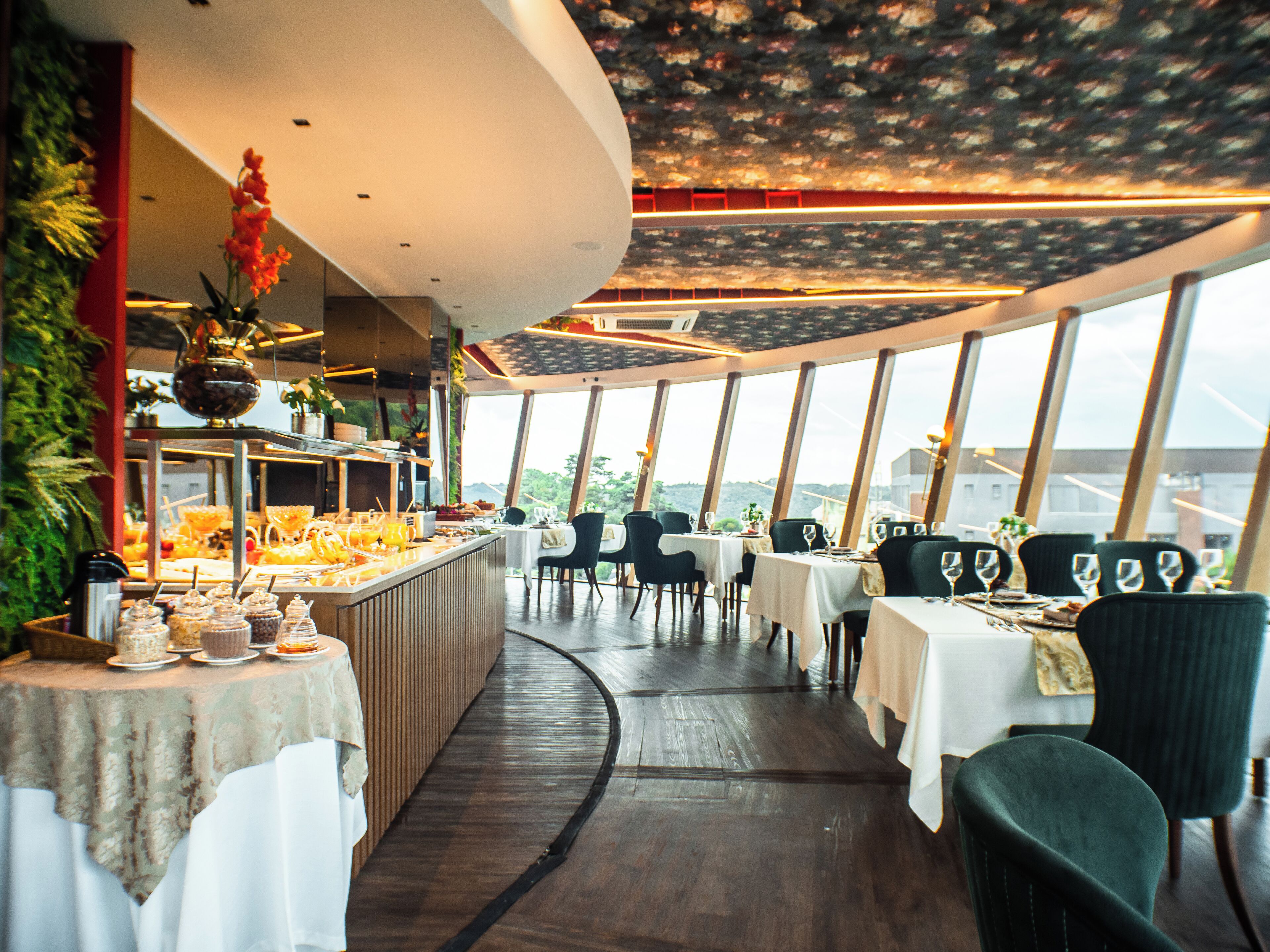 A restaurant with a curved ceiling, large windows, and a central bar area.