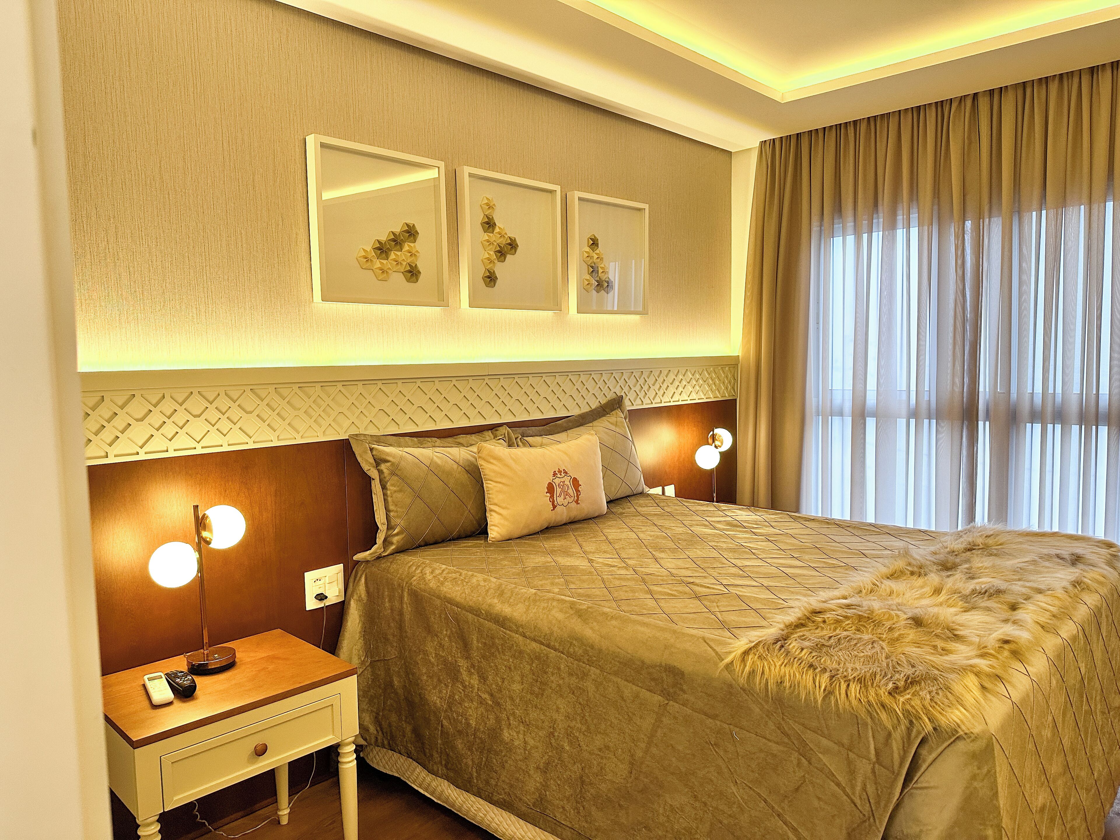 A hotel room with a large bed, bedside lamps, a nightstand, and a wall-mounted light fixture.