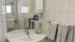 Une salle de bain moderne avec un lavabo blanc, un miroir et des murs carrelés.