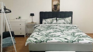 Une chambre à coucher avec un lit, une table de chevet, une lampe, une petite plante et une échelle.