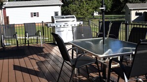 A deck with a table and chairs, an umbrella, and a grill. - At Home on South Canyon 
Newly remodeled Ranch home with plenty of space. (Rapid City)