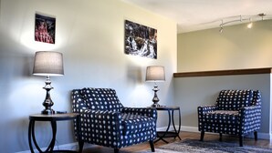 A room with two patterned armchairs, a small table, and two lamps. There are two framed pictures on the wall. - At Home on South Canyon 
Newly remodeled Ranch home with plenty of space. (Rapid City)