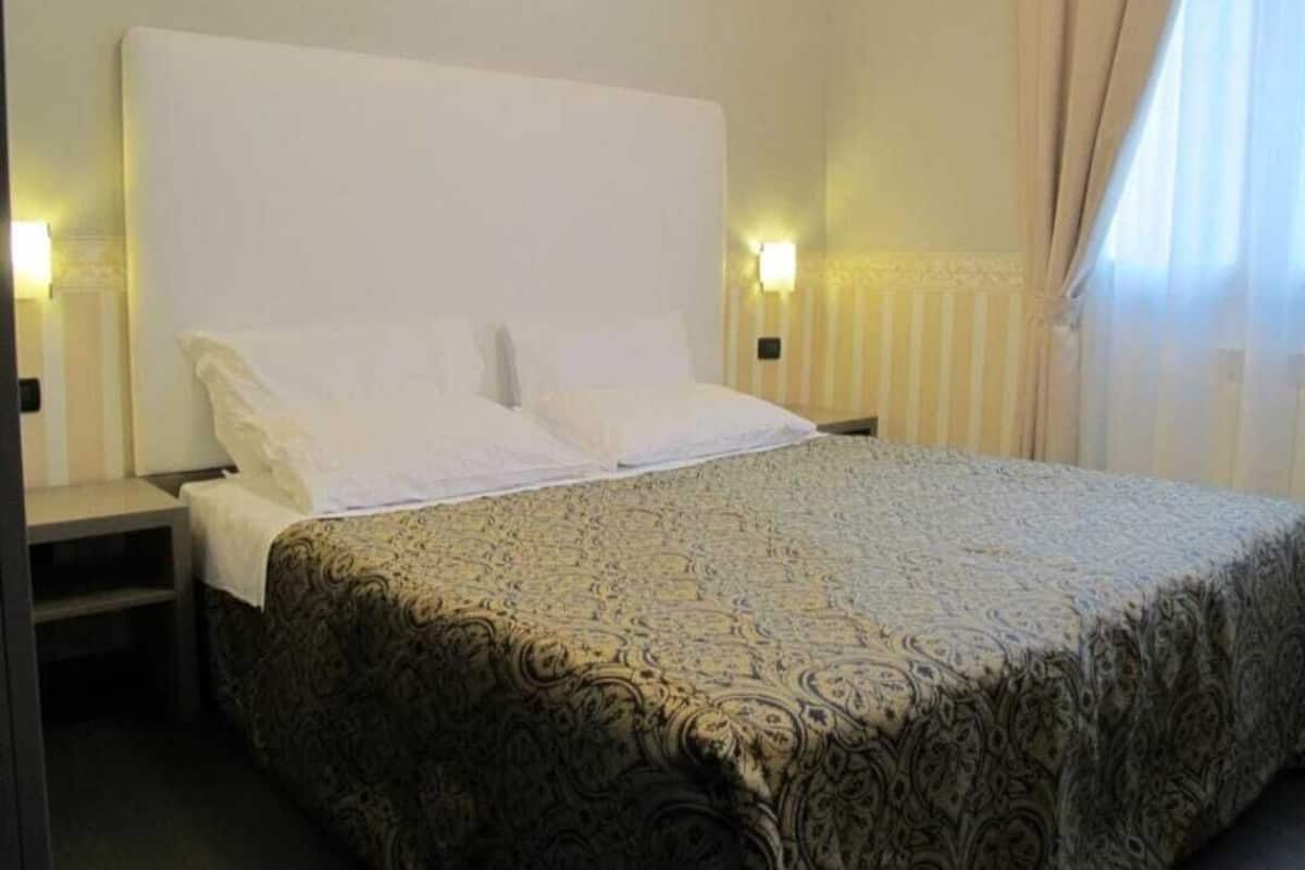 A hotel room with a large bed, two bedside tables, and a nightstand.