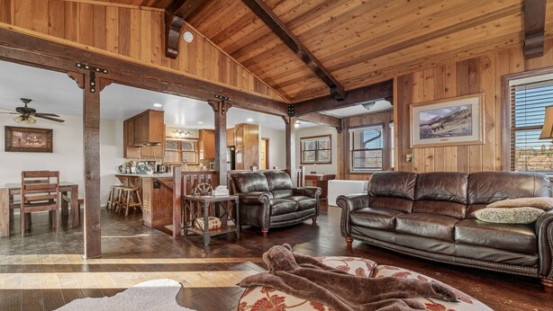 A spacious living area with leather sofas, a wooden ceiling, and a large rug. - Chateau De Bjorne (Big Bear Lake)