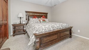 A bedroom with a wooden bed, a nightstand, a lamp, and a ceiling fan. - Chateau De Bjorne (Big Bear Lake)