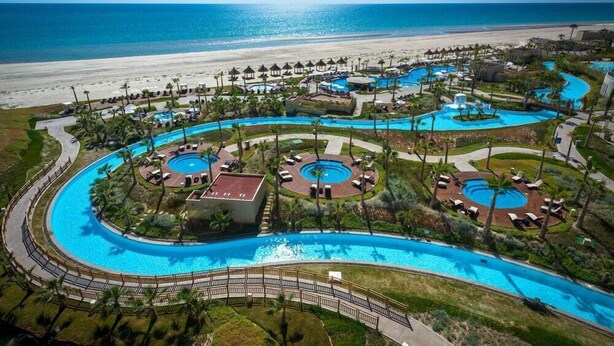Un resort con varias piscinas, una playa y vistas al océano.