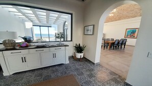 Una cocina moderna con un ventanal grande, armarios blancos y una zona de comedor con mesa y sillas.