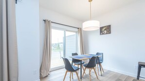En matplats med ett bord och stolar, en hänglampa och ett fönster med gardiner.