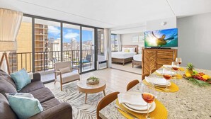 A modern hotel room with a balcony, a dining area, and a TV.