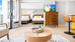 A hotel room with two beds, a dining area, a TV, and a balcony.