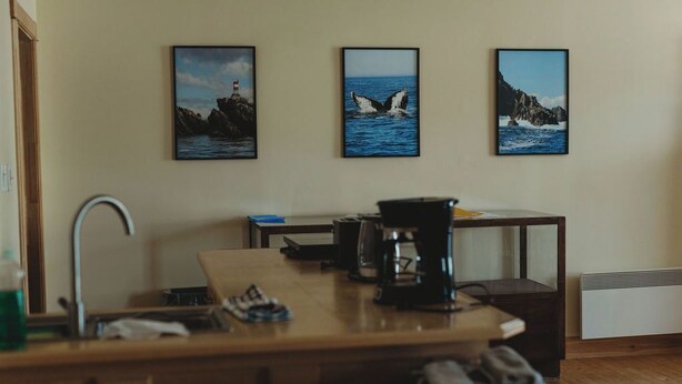A kitchen area with a wooden countertop, a coffee maker, and a sink. There are three framed pictures on the wall depicting coastal scenes. - Hectors place (Twillingate)