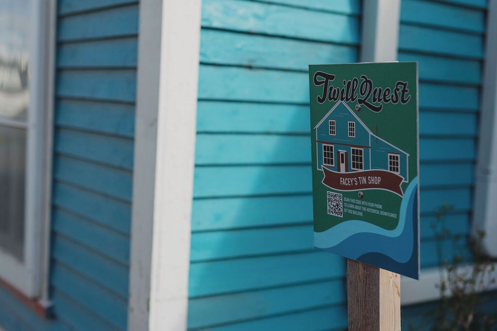 Schild für 'WillQuest Facey's Tin Shop' mit QR-Code und einer Illustration eines Hauses.