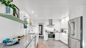 Une cuisine moderne avec des meubles blancs, des appareils en acier inoxydable et un îlot central.