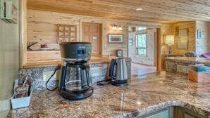 A kitchen with granite countertops, a coffee maker, and a kettle.