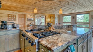 A spacious kitchen with a large island, wooden cabinetry, and a stone countertop.