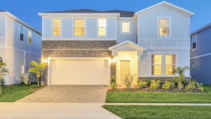 A two-story residential house with a garage, a stone accent wall, and a well-maintained lawn.