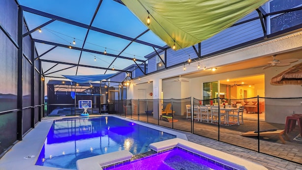 An indoor swimming pool with a glass enclosure, a hot tub, and a dining area with outdoor seating.