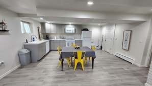 A modern kitchen with grey cabinets, a dining table with yellow chairs, and a grey floor. - Spacious & Modern Guest Apartment with Private Entrance (Smithfield)