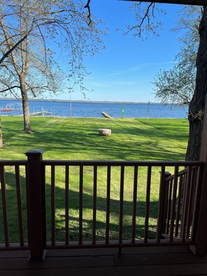 A grassy deck with a railing, overlooking a body of water with a dock and a lighthouse in the distance. - Year round home on Lake Osakis, Minnesota. (Osakis)