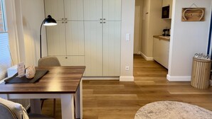 A modern kitchen with wooden cabinets, a dining table with chairs, a lamp, and a small rug. - Salzwasser - Modernes App. mit Balkon, Meerblick, Pkw-stellplatz, Wlan. Haustiere Erlaubt (List)