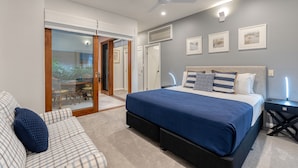 A bedroom with a large bed, a ceiling fan, and a view of the outdoors through a sliding glass door. - Villa 3 @ Chez Willow (Port Douglas)