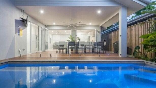 Uma área moderna de piscina interna, com ventoinha no teto, mesa de jantar com cadeiras e vista para o quarto adjacente.