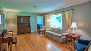 A living room with a piano, a sofa, a chair, and a cabinet.