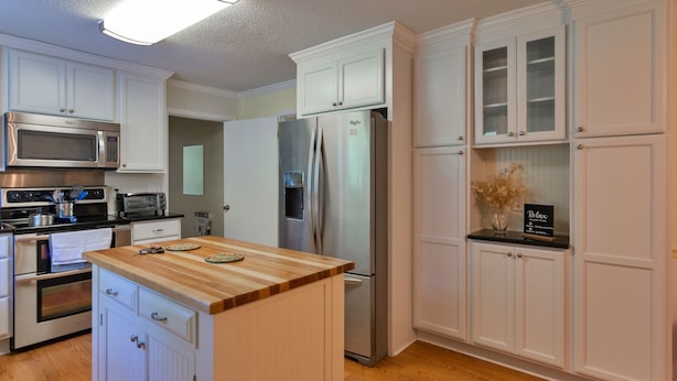 A kitchen with white cabinets, a wooden countertop, stainless steel appliances, and a built-in oven.