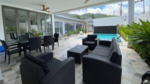 A modern outdoor patio with wicker furniture, a pool, and a view of the surrounding landscape. - Villa Oasis Tranquille 3 Chambres Avec Piscine (Rawai)