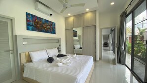 A modern hotel room with a large bed, a ceiling fan, a painting, and a view of the outdoors. - Villa Oasis Tranquille 3 Chambres Avec Piscine (Rawai)