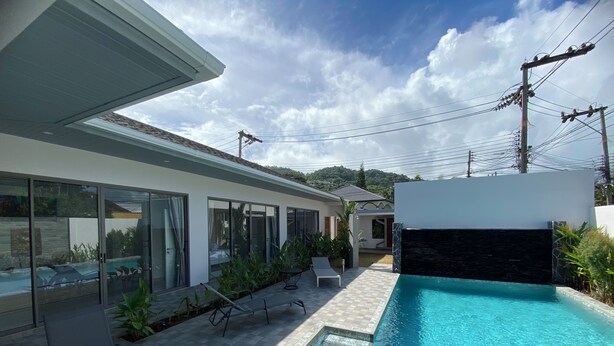 A modern outdoor pool area with a tiled deck, lounge chairs, and a clear blue pool. - Villa Oasis Tranquille 3 Chambres Avec Piscine (Rawai)
