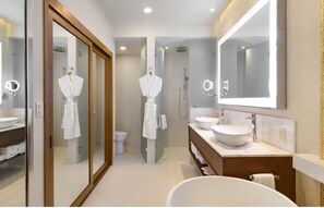 Enjoy a refreshing shower in the spacious bathroom with a walk-in shower, separate toilet area, and large mirror above the sink.