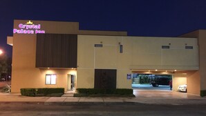 A hotel named Crystal Palace Inn with a modern design, a parking garage, and a well-lit entrance. - Crystal Palace Inn (Maywood)