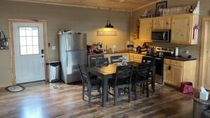 Una cocina con armarios de madera, un refrigerador, una mesa de comedor con sillas y un letrero que dice "WINE TASTING DAILY".