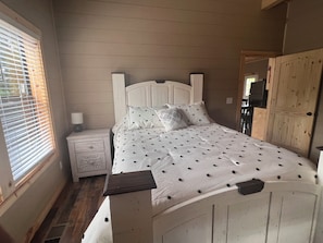 Une chambre à coucher avec un lit, une table de chevet et une fenêtre équipée de stores.