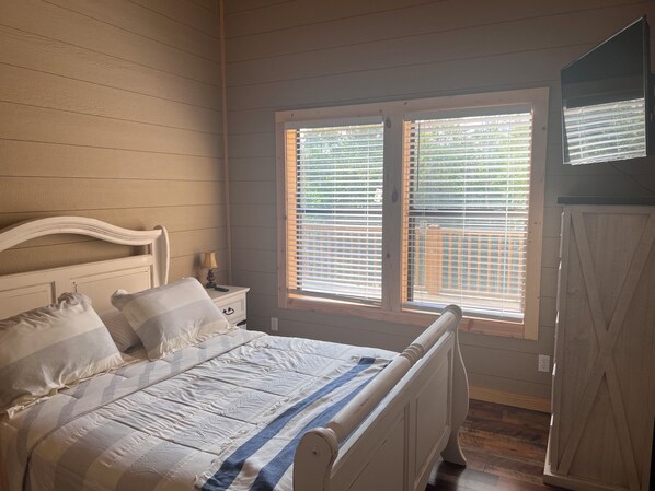 A bedroom with a bed, nightstand, and a window with blinds.