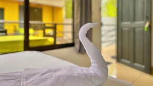 A white towel draped over a bed in a room with large windows, a view of a yellow building, and a green door. - Carey Lodging  (Colorado)