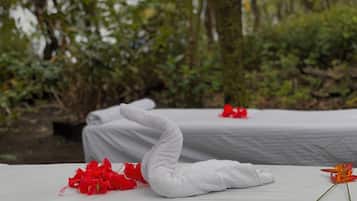 Relax in a serene outdoor setting with a neatly arranged bed area, surrounded by lush greenery and a touch of elegance.