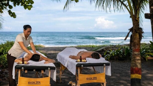 Two massage tables labeled 'evok SPA' on a beach with the ocean in the background. - Carey Lodging  (Colorado)