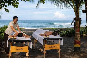 Two massage tables labeled 'evok SPA' on a beach with the ocean in the background. - Carey Lodging  (Colorado)